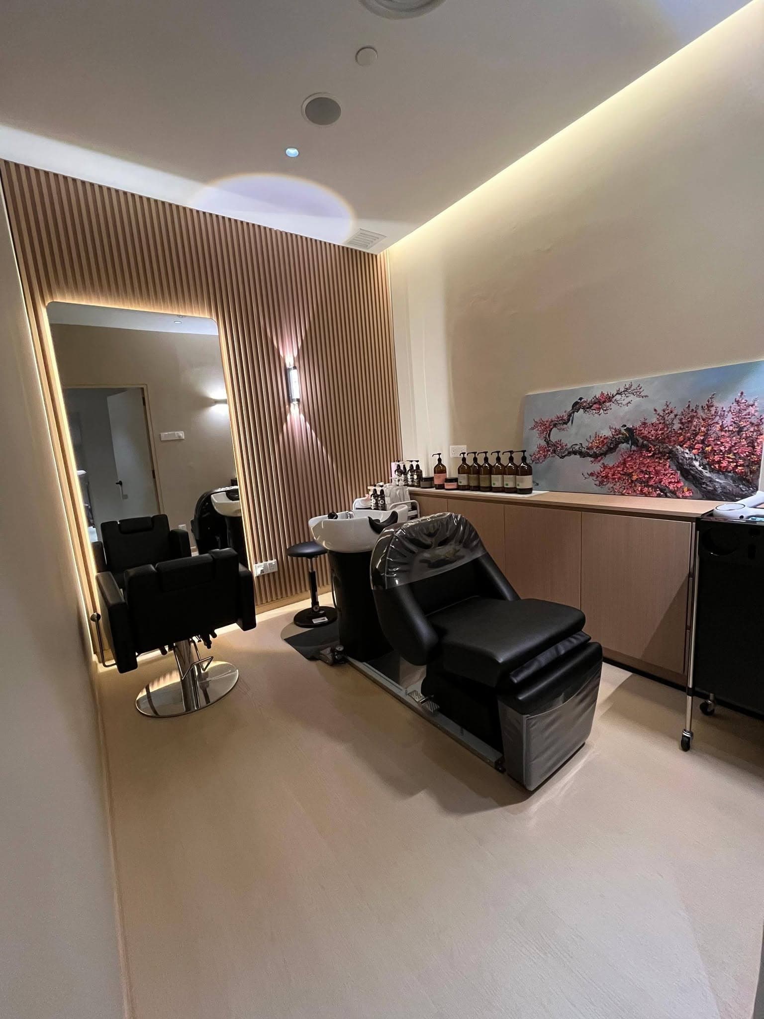 Private treatment room with backlit mirror, oak slat wall and a cherry-blossom canvas